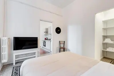a white bedroom with a bed and a flat screen tv at BDC - Termini Sun Apartment in Rome