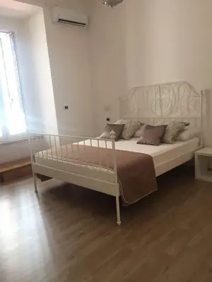 a white bed in a white bedroom with wooden floors at Appartamento vicino Stazione Termini e Colosseo in Rome