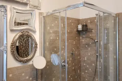 a shower with a glass door and a mirror at A casa di Juno 