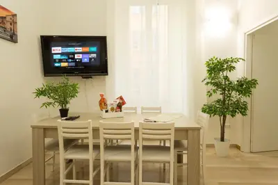 a dining room table with white chairs and a tv at San Peter Dill House in Rome