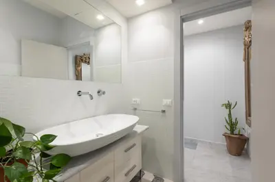 a white bathroom with a sink and a mirror at Divo Apartments - Spanish Steps in Rome