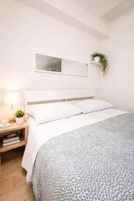 a white bedroom with a bed and a tv on the wall at Pied a Terre Barberini in Rome