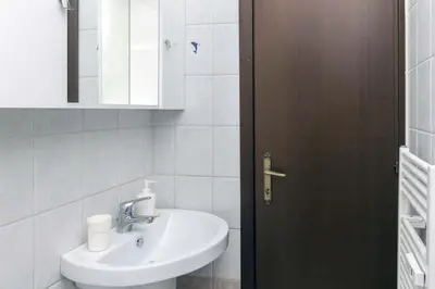 a white bathroom with a sink and a mirror at Il Cortiletto di Via Tuscolana in Rome