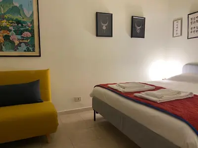 a bedroom with a bed and a yellow chair at Suite China Soul - Flaminio - Olimpico - Auditorium in Rome
