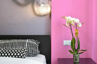 a vase of flowers on a table next to a bed at G&G Trastevere in Rome