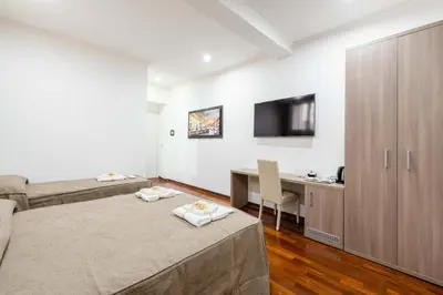 a bedroom with two beds and a desk and a tv at chèri luxury suite in Rome
