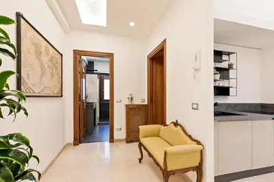 a living room with a chair and a kitchen at First Class Rome Apartments in Rome