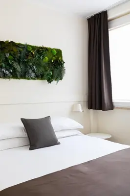 a bedroom with a bed with a plant on the wall at Demetra Eco Guest House in Rome