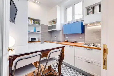 a kitchen with white cabinets and blue accents at Colosseum Terrace Apartment in Rome
