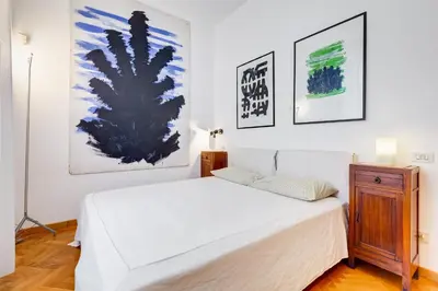 a bedroom with a white bed and paintings on the wall at Colosseum Terrace Apartment in Rome
