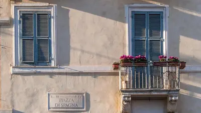 two windows with blue shutters and flowers on a building at Nido del Gambero - Your Suite with View in Rome