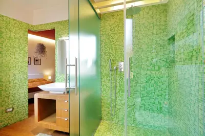 a bathroom with green tiled walls and a glass shower at Angelico Family Apartment in Rome