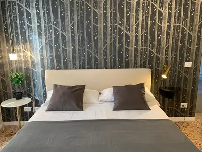 a bedroom with a bed and a wall with trees at Cavour Urban Rooms by GHOR in Rome