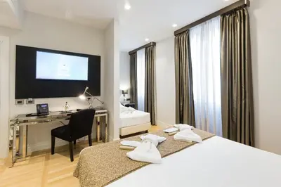 a hotel room with two beds and a desk and a television at Floris Hotel in Rome