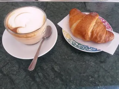a cup of coffee and a pastry on a table at La Maison In Rome in Rome