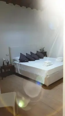 a white bedroom with two beds and a chair at Luxury House Colosseo in Rome