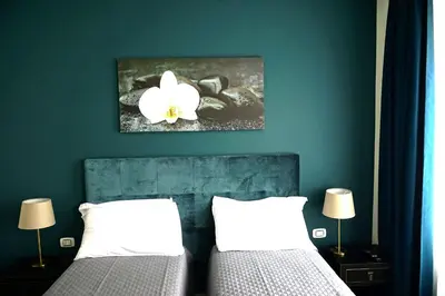 a bedroom with two beds and a flower on the wall at Regolo Rooms Vaticano in Rome