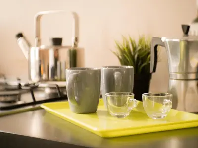 three empty glasses on a yellow tray on a kitchen counter at Charming apartment in San Giovanni 90m from Metro in Rome