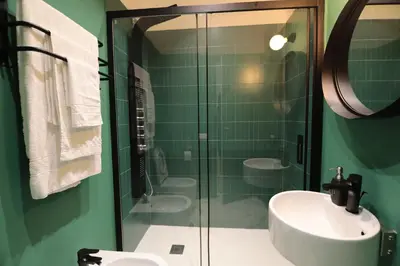 a green bathroom with a sink and two toilets at O.Effe. Suites / Vatican in Rome