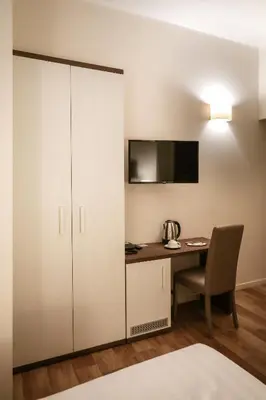 a room with a desk and a cabinet with a television at Elegant Rooms Roma - Guest House in Rome