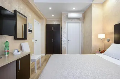 a bedroom with a bed and a desk and a door at La Meraviglia- San Pietro - Vatican Area in Rome