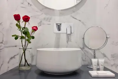 a bathroom with a vase of roses and a mirror at Fellini Design Suites in Rome