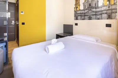 a bedroom with a white bed with two pillows on it at B&B Hotel Roma San Lorenzo Termini in Rome