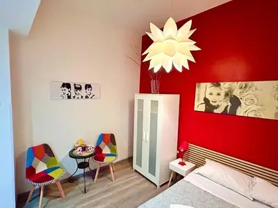 a bedroom with a red wall with a bed and chairs at Core De Roma Suites in Rome