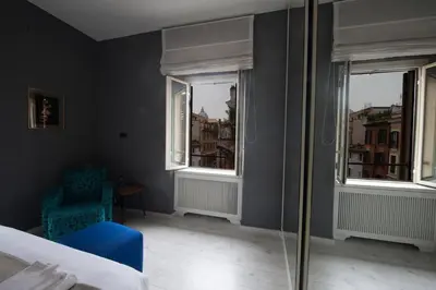 a bedroom with a blue chair and two windows at Vatican Color House in Rome