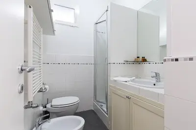 a white bathroom with a toilet and a sink at Emma's Apartment Borgo, Vatican City in Rome