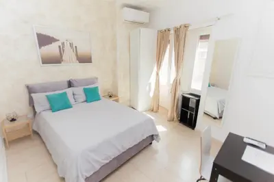 a bedroom with a bed with blue pillows and a desk at San Pietro Home in Rome