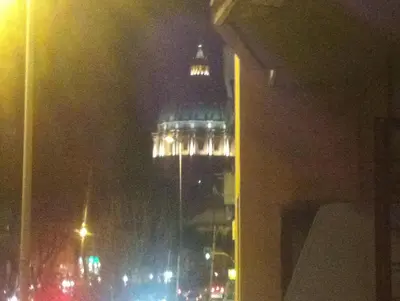 a tall building with lights on it at night at San Pietro Home in Rome