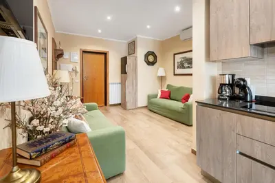 a living room with a green couch and a kitchen at ROMAN DREAM I in Rome