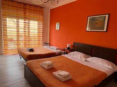 two beds in a room with orange walls at Bibbi's House San Lorenzo in Rome