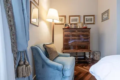 a bedroom with a blue chair and a dresser at Colonna Traiana - The View Boutique Luxury Home in the center of ancient Rome in Rome