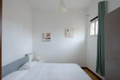 a white bedroom with a bed and a window at Trastevere Heart Home in Rome