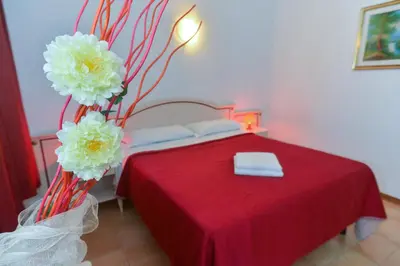 a bedroom with a bed with a red table with flowers at Gisa Apartment in Rome