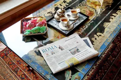 a table with a newspaper and cups and a book at TreasureRome Daphne Terrace in Rome