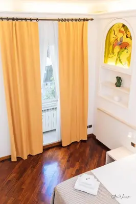 an orange curtain in a room with a window at Magik rooms in Rome