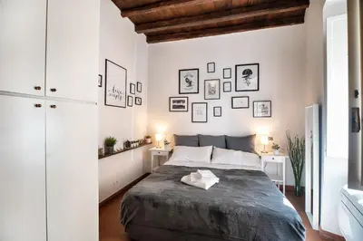 a white bedroom with a large bed and pictures on the wall at Appartamento via dei Baullari in Rome