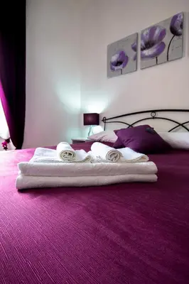 a bedroom with a purple bed with towels on it at Casa Via Cesena in Rome