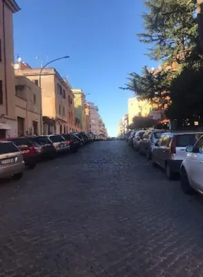 a cobblestone street with parked cars in a city at New Suite Amèlie in Rome