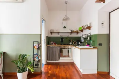 a kitchen with green and white walls and wooden floors at New Suite Amèlie in Rome