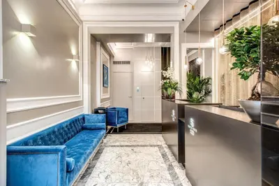 a blue couch in a waiting room with plants at Hotel 55 Fifty-Five - Maison d'Art Collection in Rome
