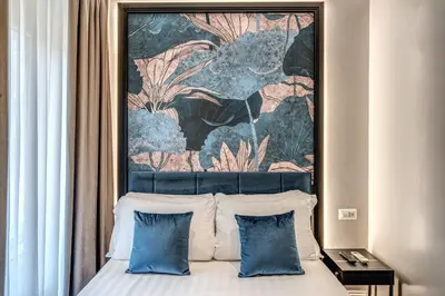 a bed with two blue pillows and a tapestry above it at Hotel 55 Fifty-Five - Maison d'Art Collection in Rome