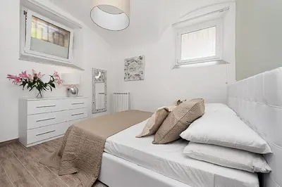 a white bedroom with a bed and a dresser at BMGA l Mon Amour San Giovanni Apartment in Rome