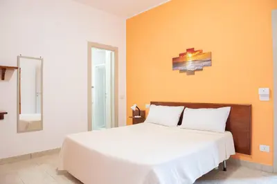 a bedroom with a white bed with an orange wall at Da Merion in Rome
