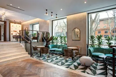 a lobby with green chairs and tables and windows at DoubleTree By Hilton Rome Monti in Rome