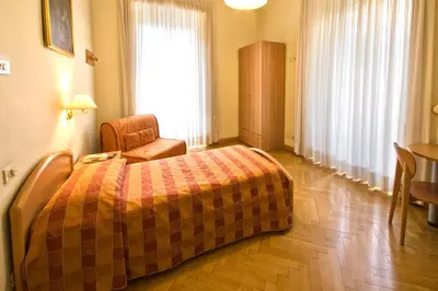 a bedroom with a bed and a chair and a window at Gästehaus Deutscher Orden in Rome
