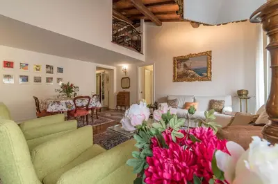a living room with green furniture and pink flowers at Quiet and classic on two floors, by Trevi Fountain - FromHometoRome in Rome